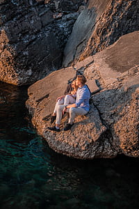 couple sitting on the edge of rock thumbnail