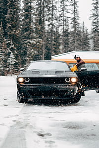 man near opened black Dodge Challenger on snowfield thumbnail