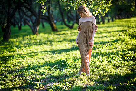 woman wearing off-shoulder jumpsuit walking on green grass field thumbnail