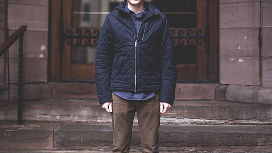 person in blue jacket and brown pants standing by close doors thumbnail