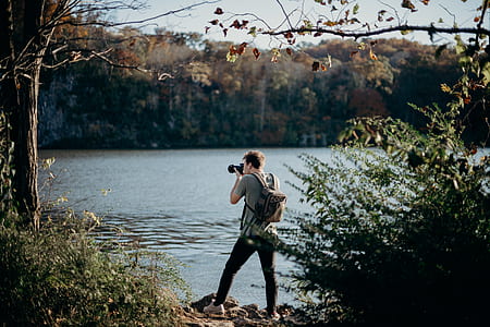 man taking photograph near water thumbnail