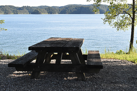 rectangular brown wooden table and bench beside body of awter thumbnail