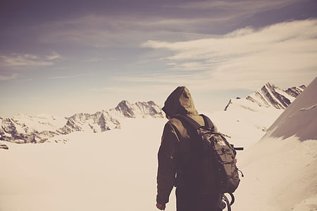 man with black backpack walking on field covered by snow at daytime thumbnail