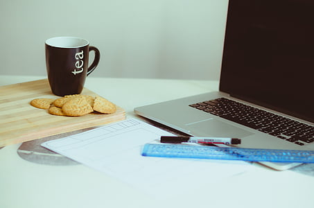 brown ceramic mug beside cookies near gray laptop computer on white surface thumbnail