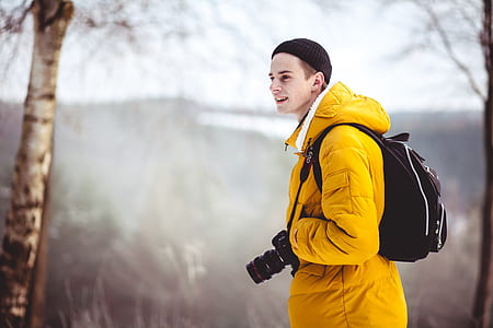 man wearing yellow bubble jacket and backpack thumbnail