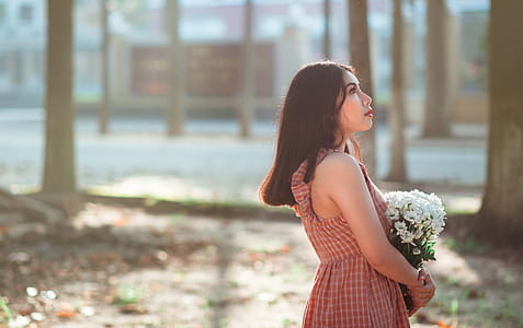 Woman Wearing Brown Sleeveless Dress Carrying White Flower Bouquet thumbnail