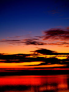 calm body of water under orange and black sky during golden hour thumbnail