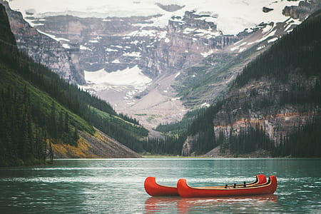 two canoes on calm body of water fronting mountain covered with snow thumbnail