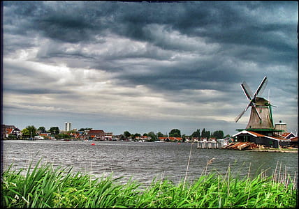 brown windmill near body of water during daytime thumbnail