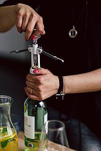 Hands opening wine bottle with corkscrew thumbnail