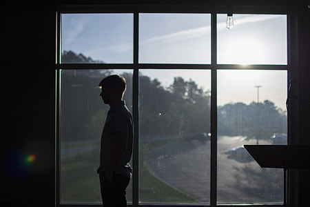 man standing beside window thumbnail