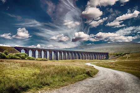 landscape timelapsed photography of concrete bridge in the middle of mountains during cumulus clouds thumbnail