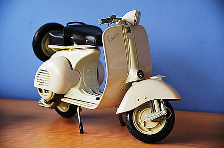 white and black motor scooter miniature on brown wooden surface thumbnail