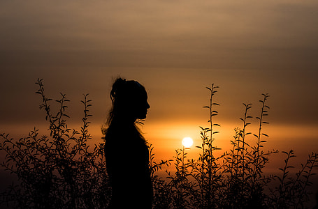 person standing in tall grass field during sunset thumbnail