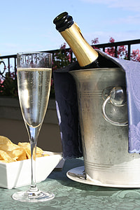 clear champagne flute full of wine beside round gray metal ice bucket thumbnail