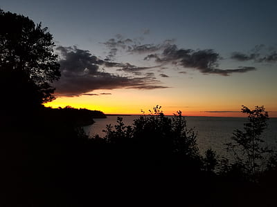 Body of Water Near Trees Under Orange Sunset thumbnail