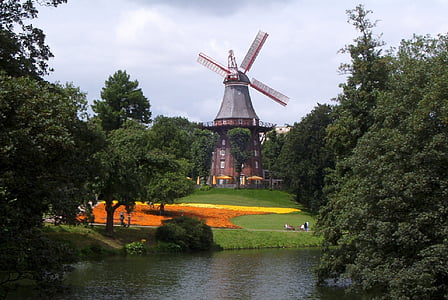 wind mill near trees and river thumbnail