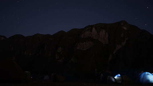 assorted-color dome tents at night near mountain thumbnail