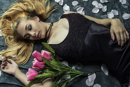 woman lying beside pink petaled flowers thumbnail