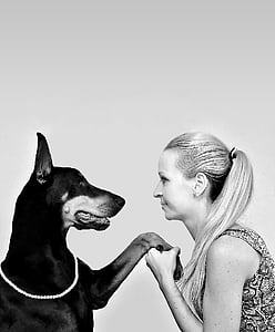 woman holding left foot of Doberman pinscher greyscale photography thumbnail