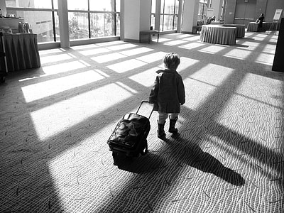 gray-scale photo of toddler's walking away dragging luggage thumbnail