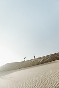 two men walking on dessert against gray and blue sky during daytime thumbnail