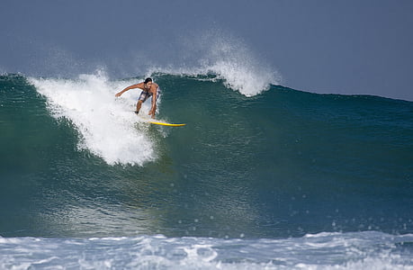 person surfing the wave with yellow surfboard under clear sky thumbnail