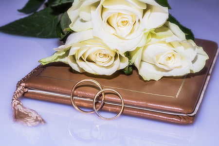 two gold-colored couple ring on book with bouquet thumbnail
