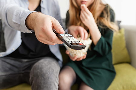 Happy young couple sitting and watching TV at home thumbnail