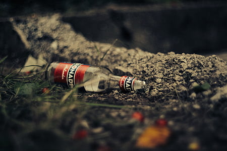 empty red labeled bottle on soil thumbnail