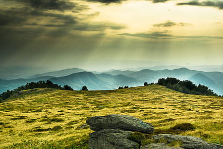 green field and trees near mountains during daytime thumbnail