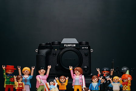 black Fujifilm DSLR camera surrounded with action figures on black surface thumbnail