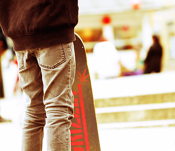 selective focus photography of person in black top and gray jeans with gray skateboard thumbnail