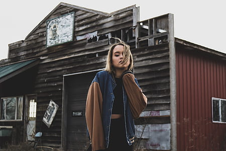woman wearing blue and brown jacket standing near house thumbnail