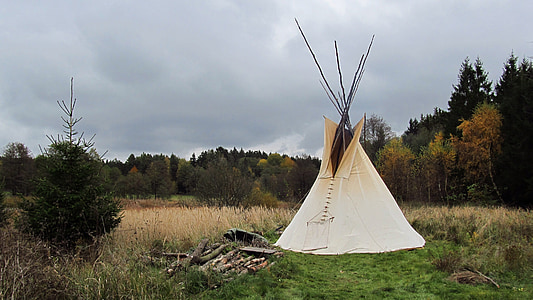 white teepee tent on green field surrounded by trees at daytime thumbnail