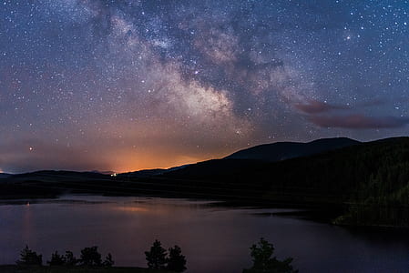 lake surround by mountains under sky with stars thumbnail