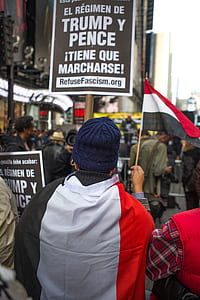 person holding red and white flaglet walking with crowd thumbnail