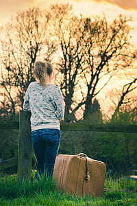 woman wearing gray long-sleeved shirt and blue jeans beside brown travel luggage thumbnail