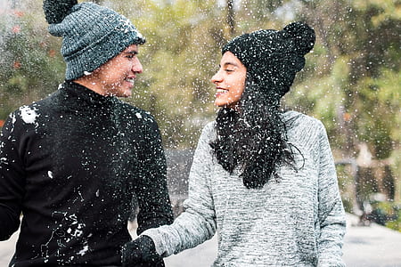 man and woman wearing sweaters and knit caps walking on snow facing each other selective-focus photography thumbnail