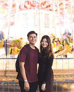 man standing beside woman standing beside carousel thumbnail