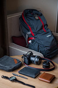 black DSLR camera beside leather notebook, brown wallet, click pen, and watch place on table thumbnail