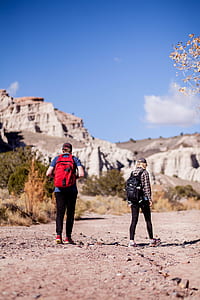two women walking towards rock formation under sunny day thumbnail