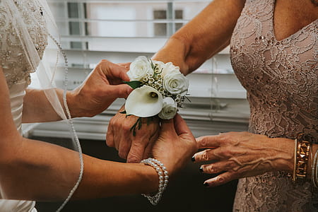 bride put white floral wrislet on her mother's right wrist thumbnail