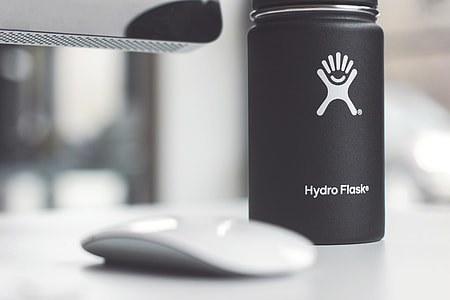 black Hydro Flask airtight jar on top of white surface near Apple Magic Mouse thumbnail