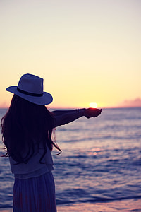woman wearing white fedora hat standing near seashore during sunset thumbnail