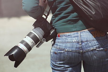 woman holding black and white DSLR camera and black leather handbag thumbnail