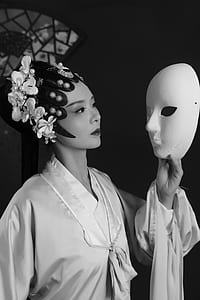 black and white photo of woman holding mask thumbnail