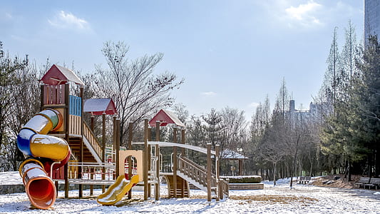 red, blue, and yellow slide playground covered with snow thumbnail