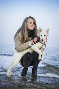 woman with white German shepherd near calm body of water at daytime thumbnail