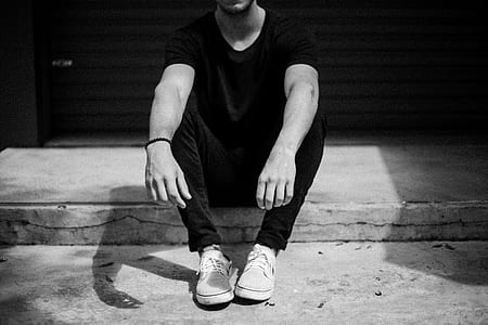 grayscale photo of man sitting on pavement thumbnail